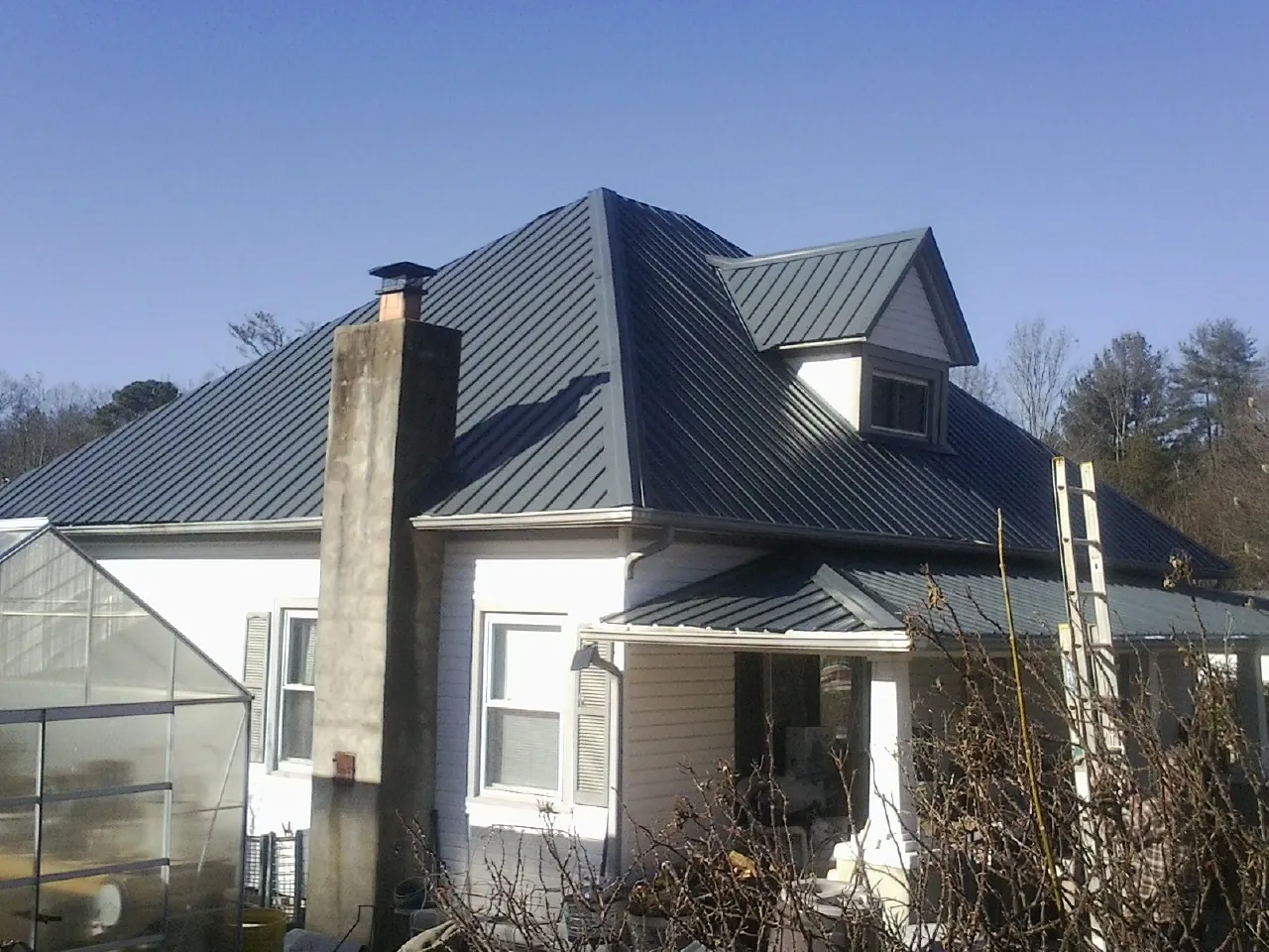 Dark blue standing seam metal roof on a white farmhouse with dormer — Slate & Tile Roof Repair by Roofing Brothers in Porterville