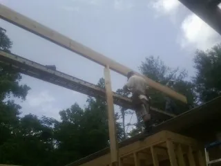 Carpenter setting a ridge beam over a new addition frame — Ice Dam Removal by Roofing Brothers in Porterville
