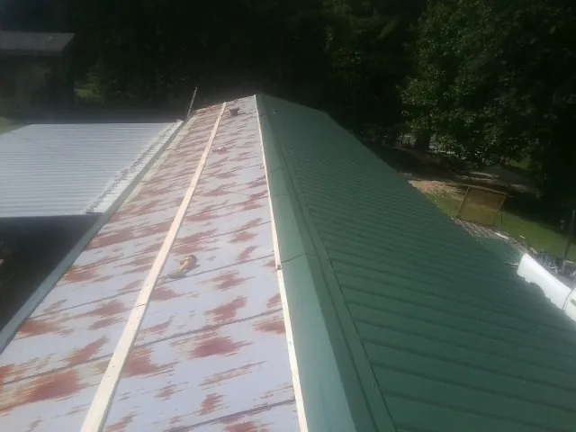 Old rusted panels beside newly installed green metal roofing — Wind Damage Roof Repair by Roofing Brothers in Porterville