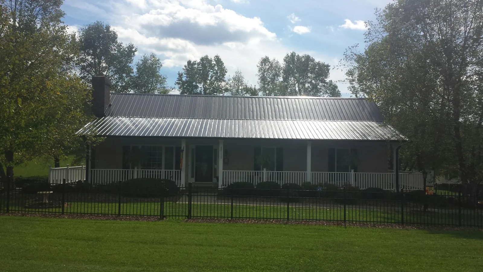 Gray metal roof on a brick ranch with a full width front porch — Gutter Guard Installation work by our crew in Porterville