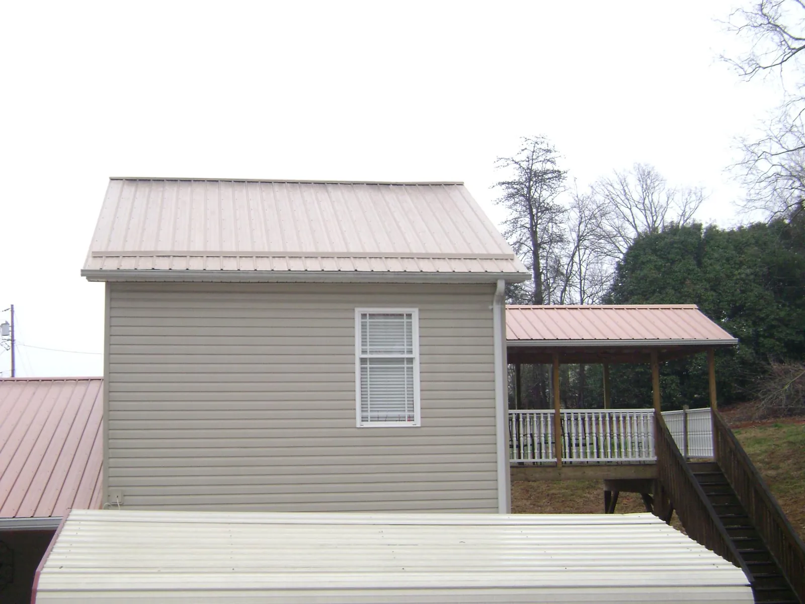 Tan metal roofs on a two story addition and attached porch, from a Roof Replacement job in Porterville