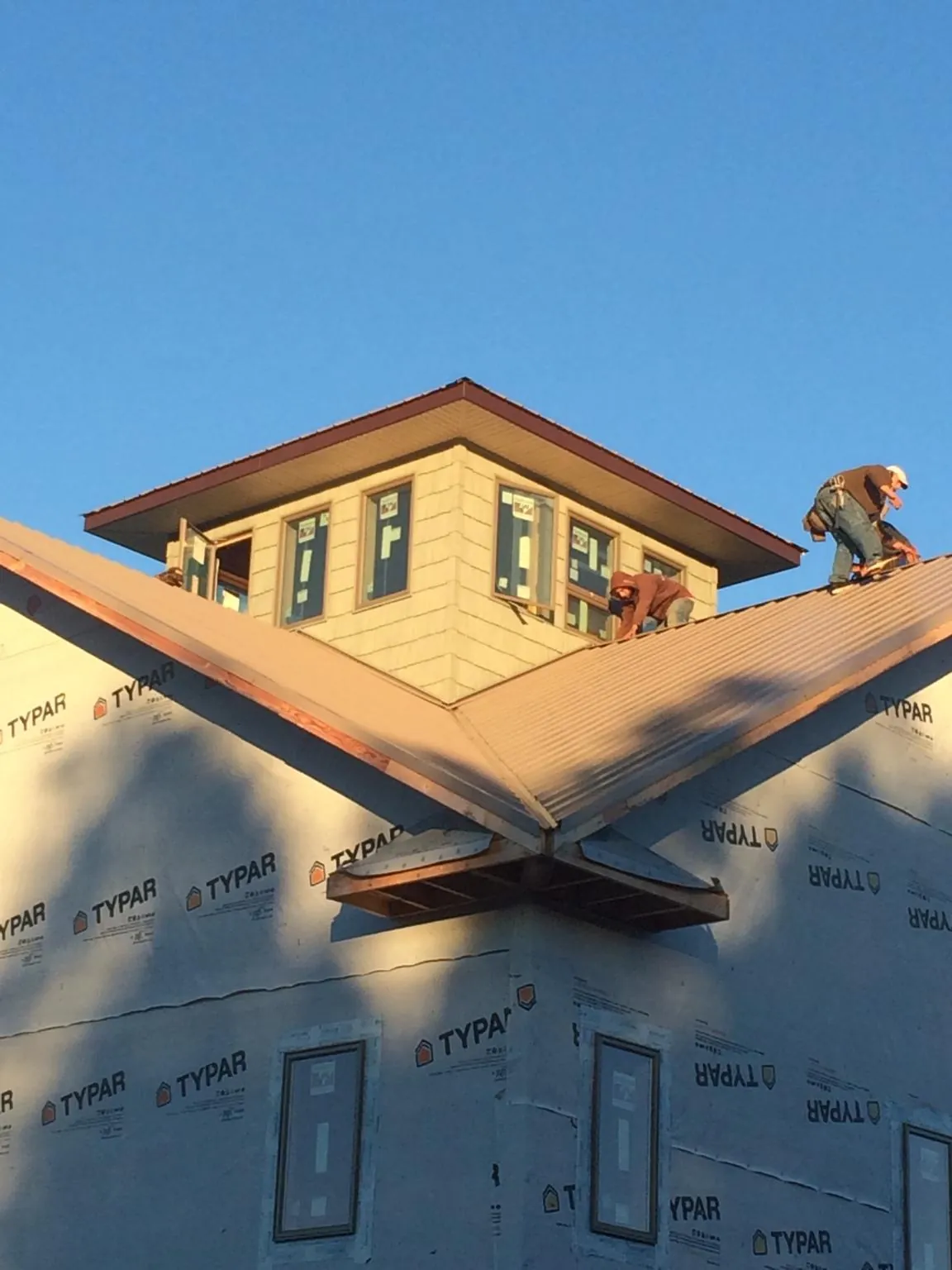 Roofers working around a rooftop cupola on a new metal roof at sunset — Roof Waterproofing in Porterville by Roofing Brothers
